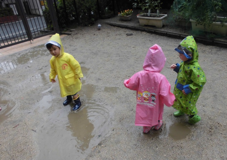 雨の日の園庭散歩。雨の音、水たまりに入る楽しさ。様々な経験が子どもの興味・関心を引き出します。